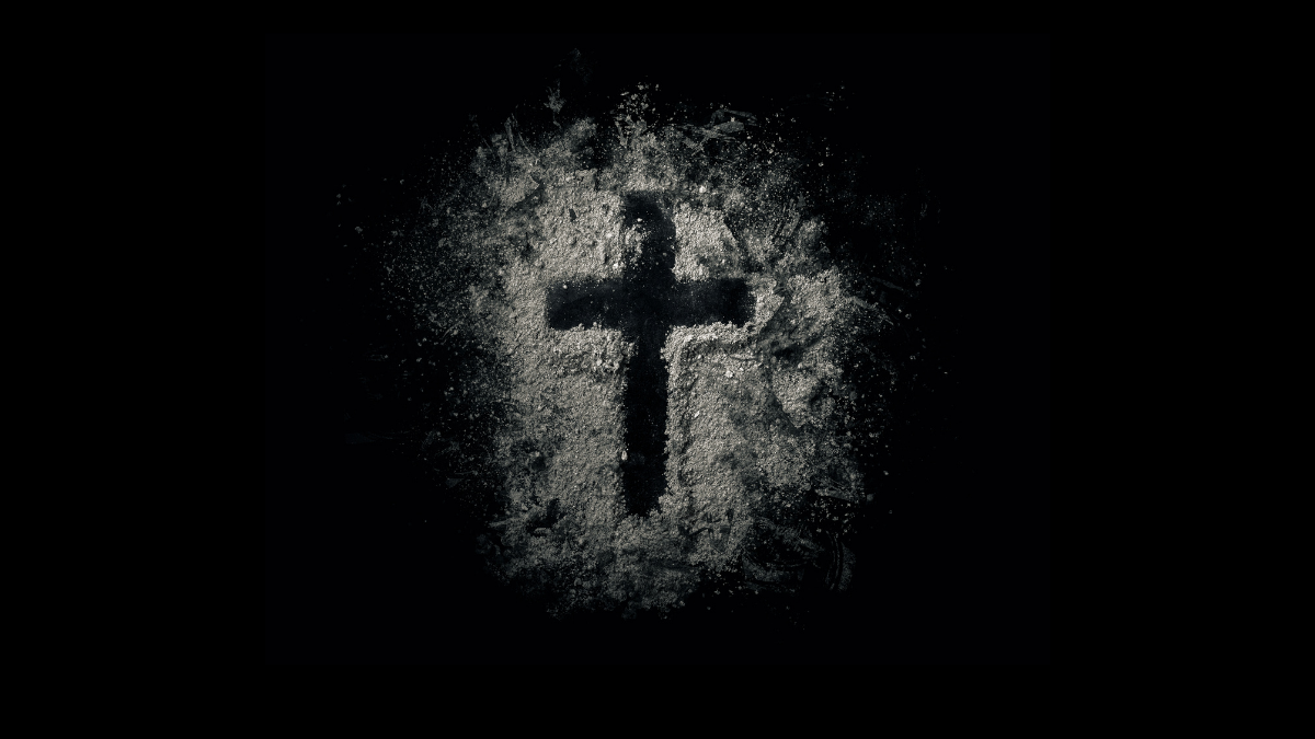 cross drawn on a black background with ashes